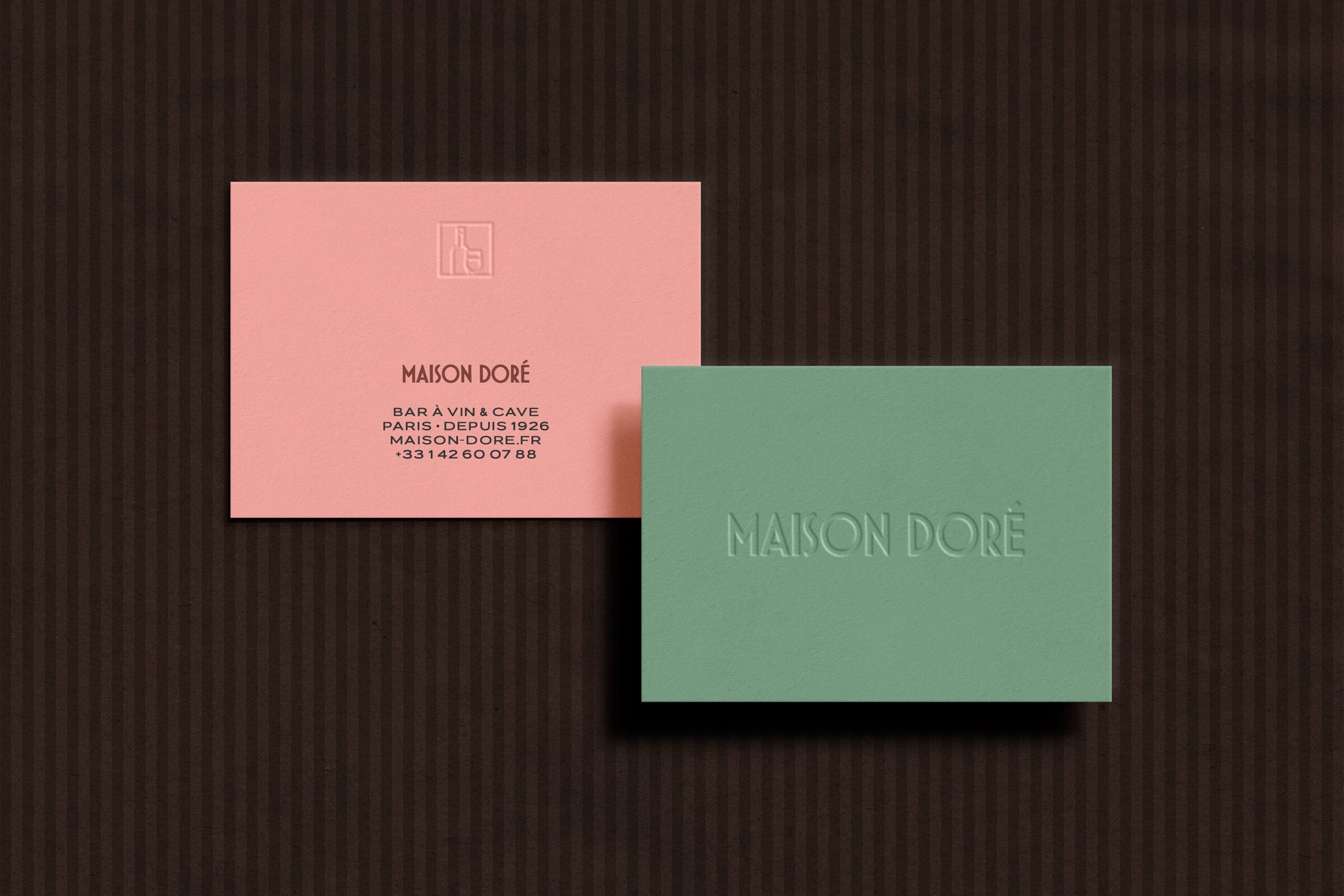 Maison Doré business cards in pink with embossed logo, green card with debossed text on dark striped background