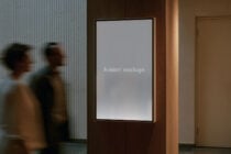 Framed display screen in modern hallway with blurred people walking by, wood paneling