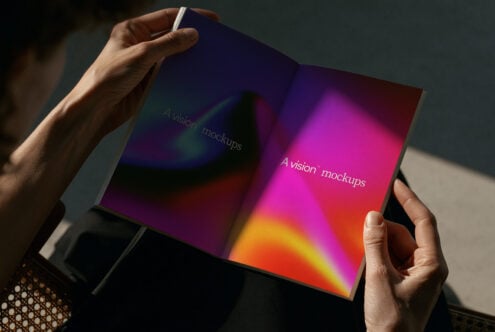 Hands holding open magazine with vibrant gradient from purple to orange, displaying text overlay