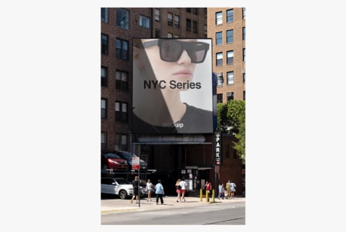 Large billboard mockup on NYC building facade showing sunglasses product with street scene below