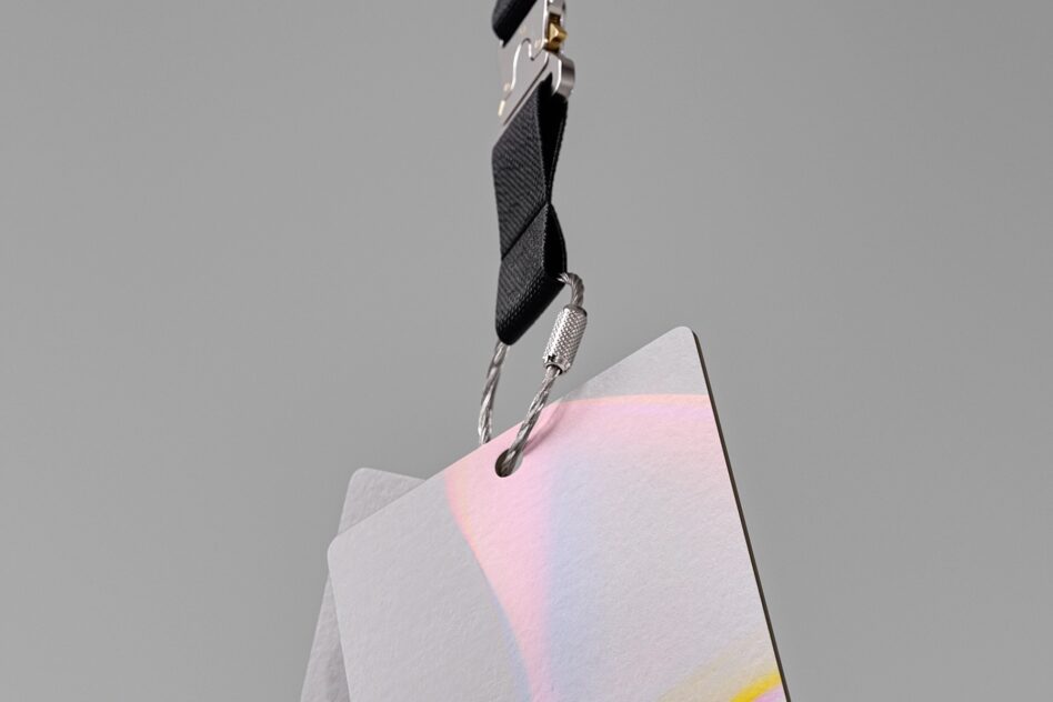 Blank ID card mockup hanging from black lanyard with metal clips on neutral background