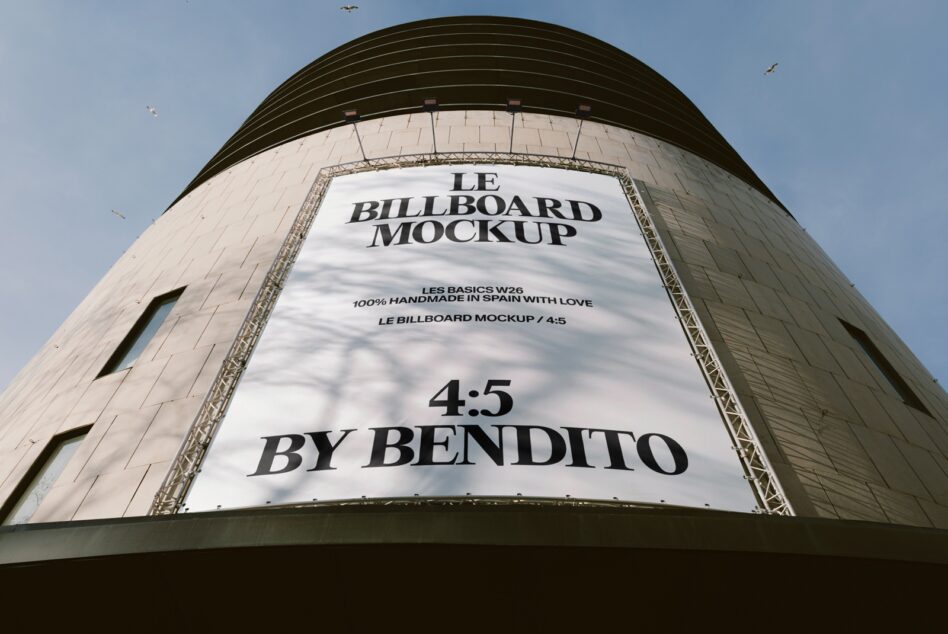 Curved billboard on cylindrical building tower showing serif typography mockup against clear sky