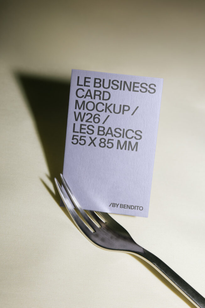 Lavender business card mockup balanced on a fork, casting sharp shadows on cream background