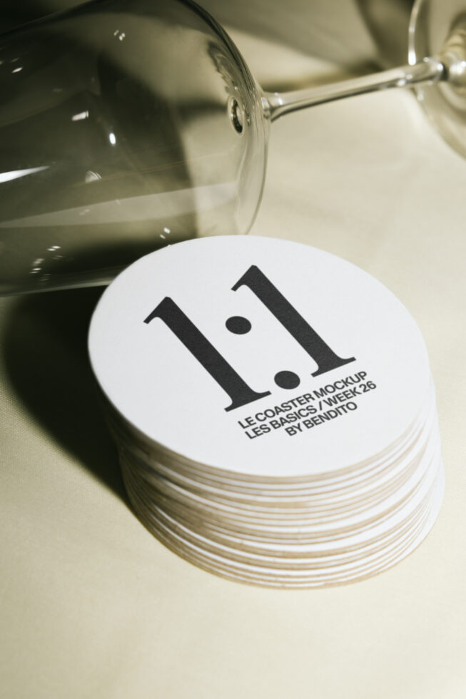 Stack of round coasters with minimalist branding design, wine glass pouring overhead