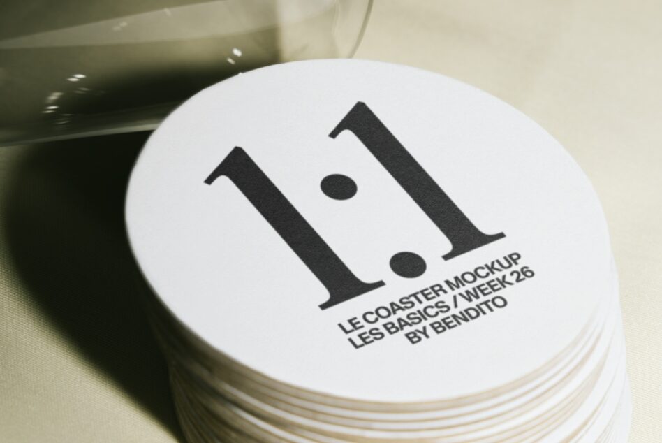Stack of white coasters with bold black serif letter I logo printed on top surface