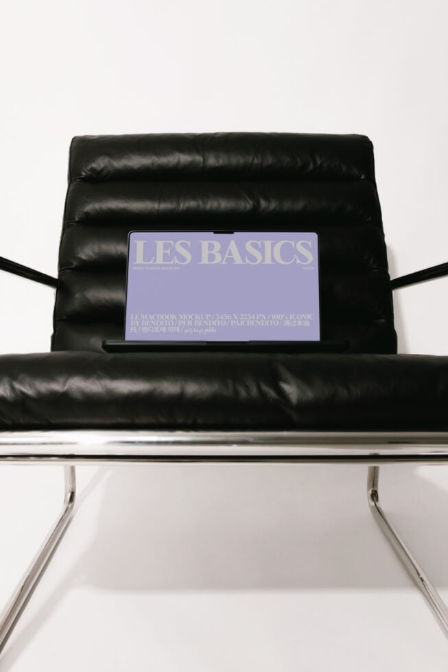 Laptop screen mockup on black leather chair showing purple Les Basics design
