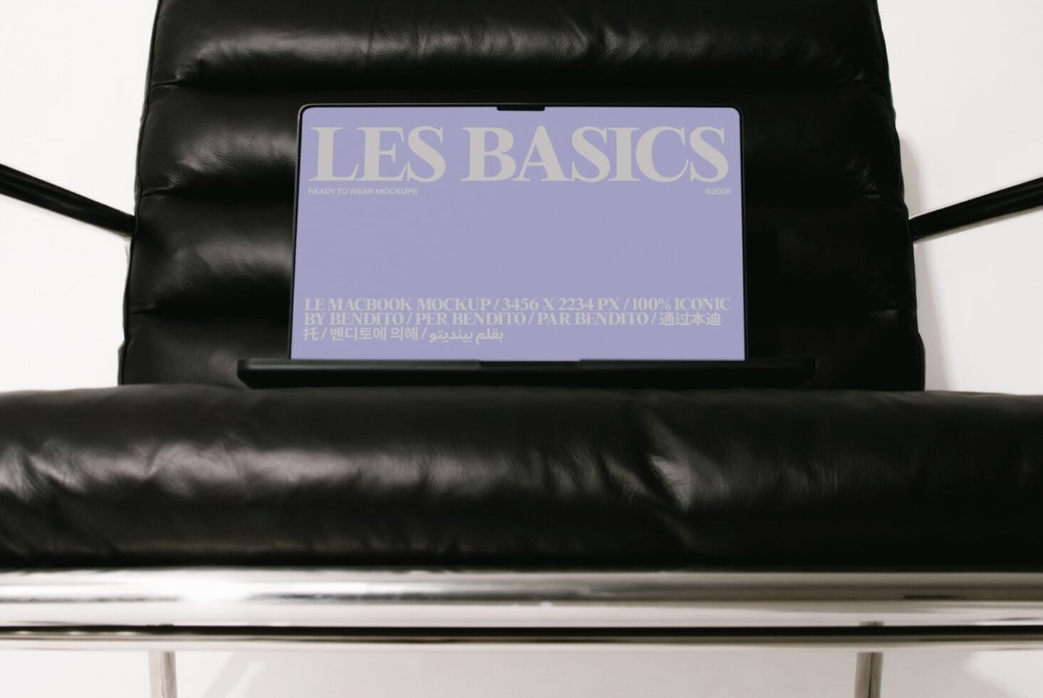MacBook mockup on black leather couch showing Les Basics purple screen design with multilingual text