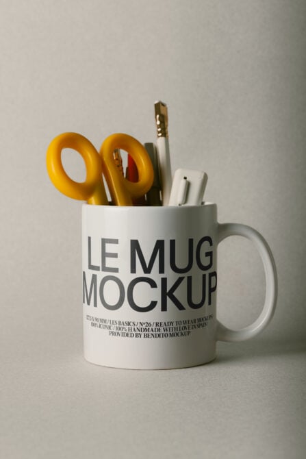 White mug mockup filled with gold scissors, pens, paintbrush against neutral background