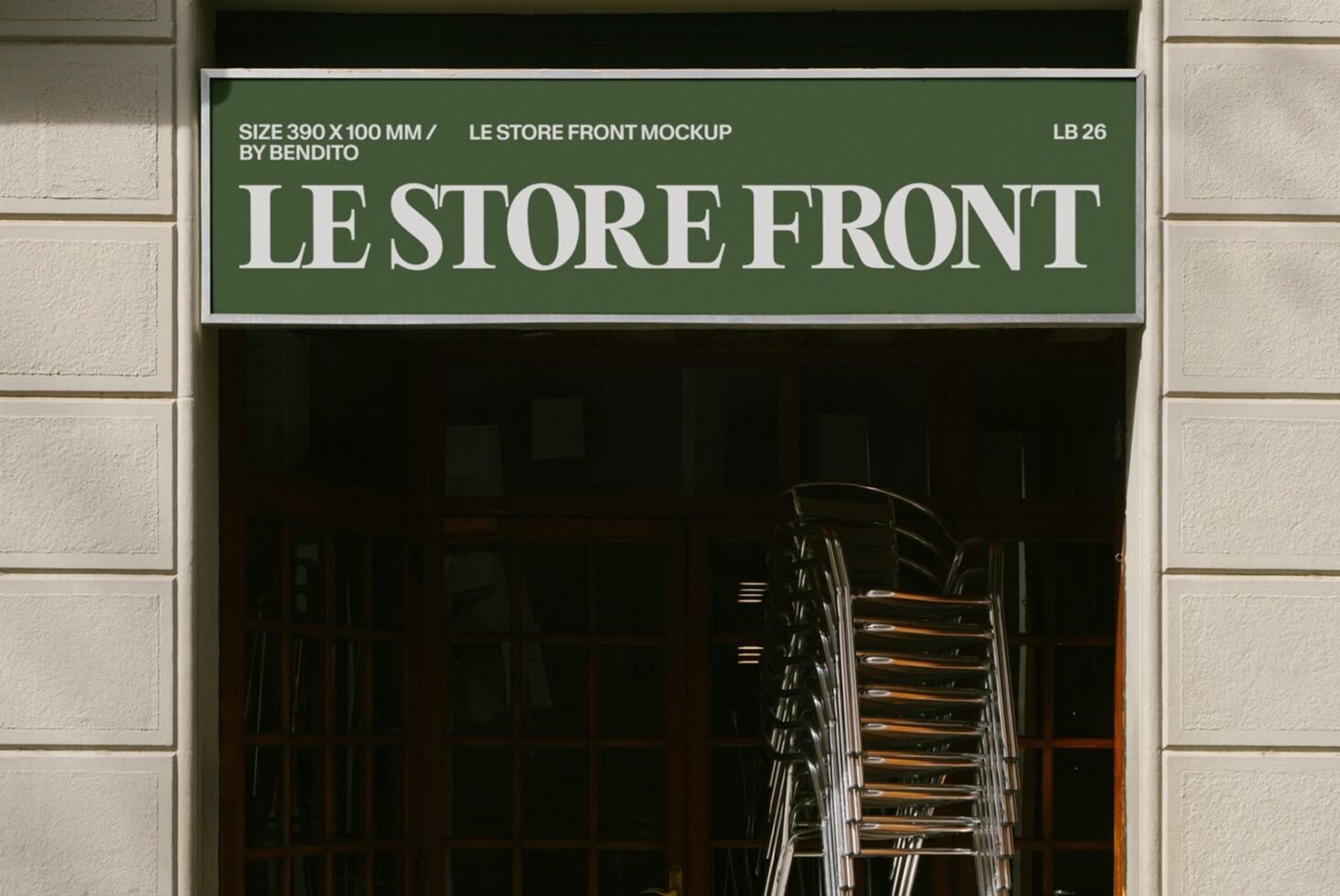 Green storefront sign with white serif lettering on cream brick facade, stacked chairs visible through dark window