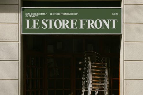 Green storefront sign with white serif lettering on cream brick facade, stacked chairs visible through dark window