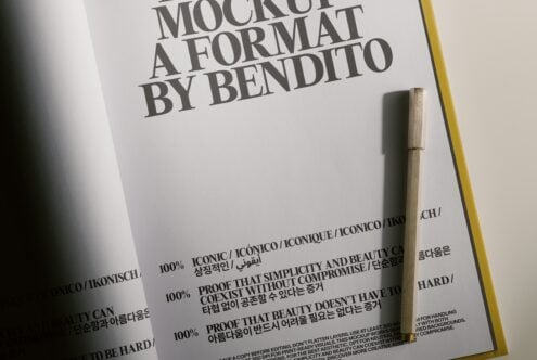 Minimalist book cover mockup with serif typography, wooden pen, multilingual text on cream paper with yellow spine edge