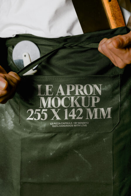 Olive apron mockup with pocket showing ceramic plate, wooden spoon propped nearby
