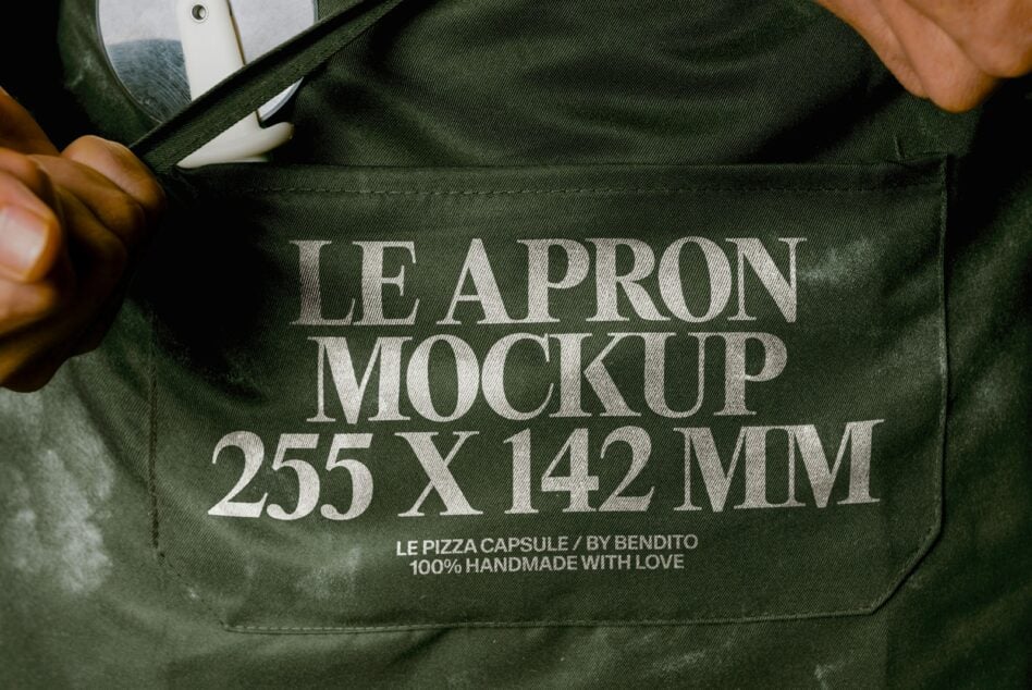 Olive linen apron with serif typography mockup, dimensions displayed, styled flat lay with pen