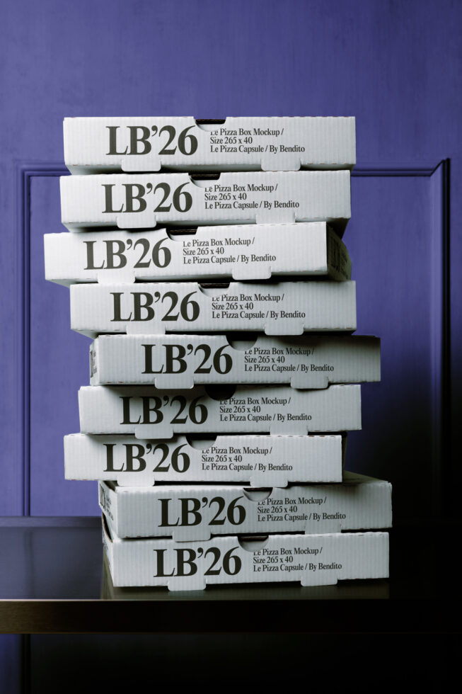 Stacked white pizza boxes with LB'26 branding against deep blue wall showing realistic shadows