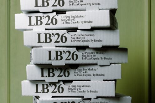 Stacked white pizza boxes with bold serif typography against soft green background