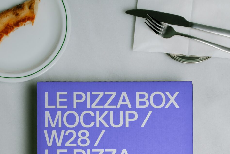 Overhead shot of pizza box mockup in bright blue with plate of pizza slice, fork, knife, plus napkin on white surface
