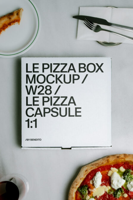 Overhead shot of pizza box mockup styled with actual pizza slices, plates, cutlery on white surface