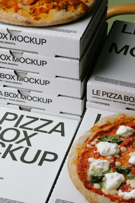 Stacked pizza boxes with fresh pies on top, showing label mockups from above with natural lighting