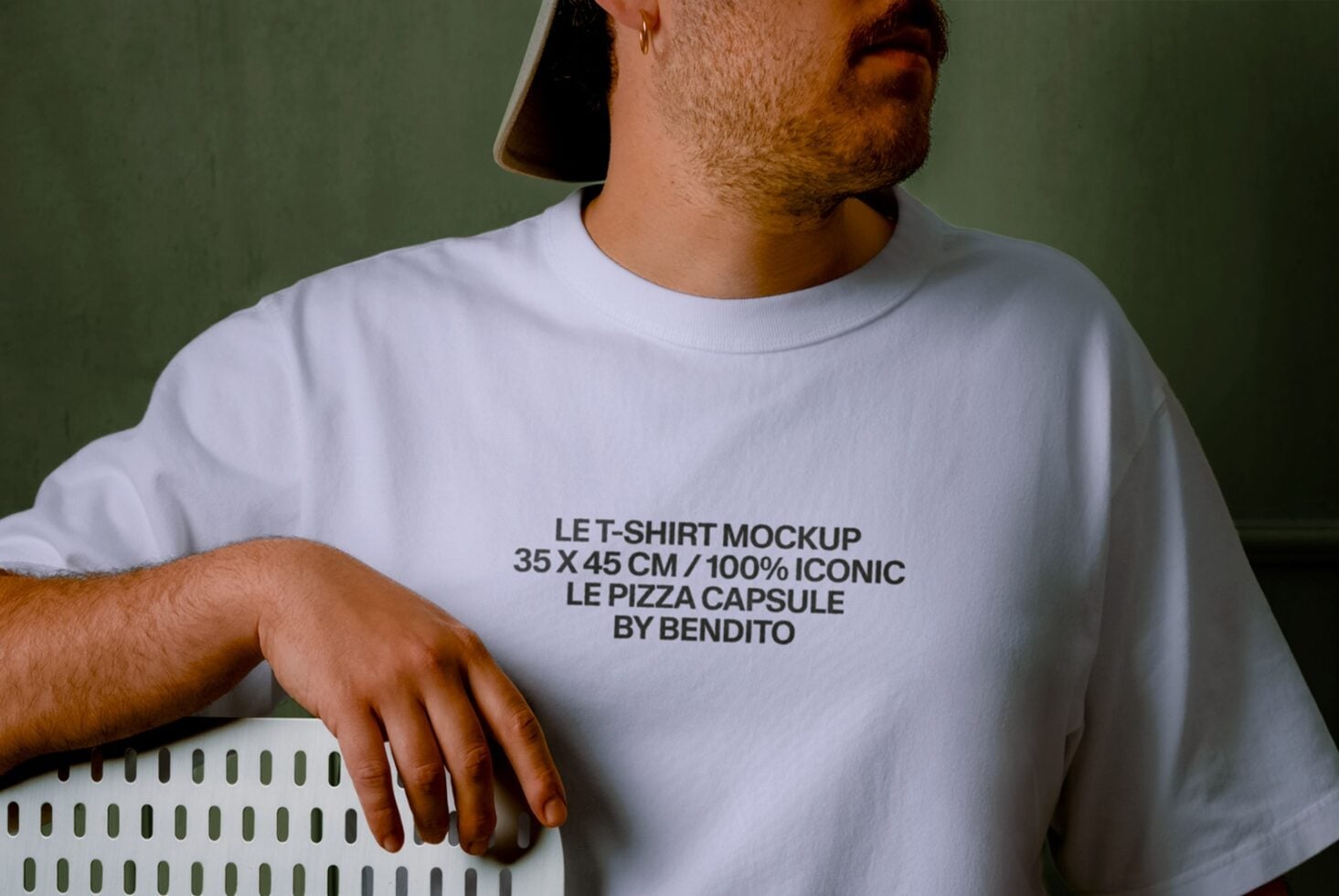 Guy wearing white tee with text design against olive green background, relaxed pose