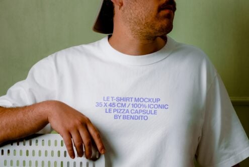 Guy in white tee against sage green background, text placement on chest, relaxed pose