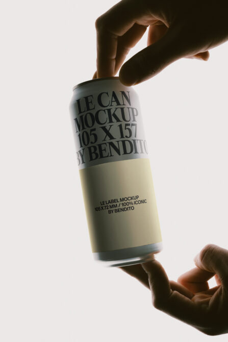 Hands holding up a beverage can with wraparound label mockup against white background