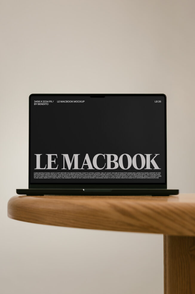 MacBook mockup sitting on wooden desk with black screen displaying "LE MACBOOK" typography