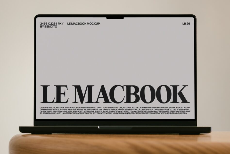 MacBook mockup with minimalist serif typography layout on screen, wooden desk surface