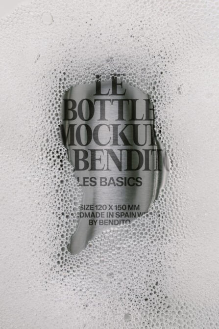 Frosted glass bottle mockup with condensation droplets, label shows product text centered on wet surface
