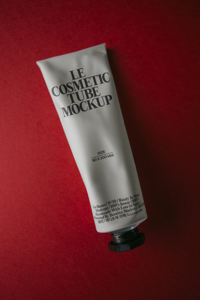 White cosmetic tube with black cap on deep red background, angled view