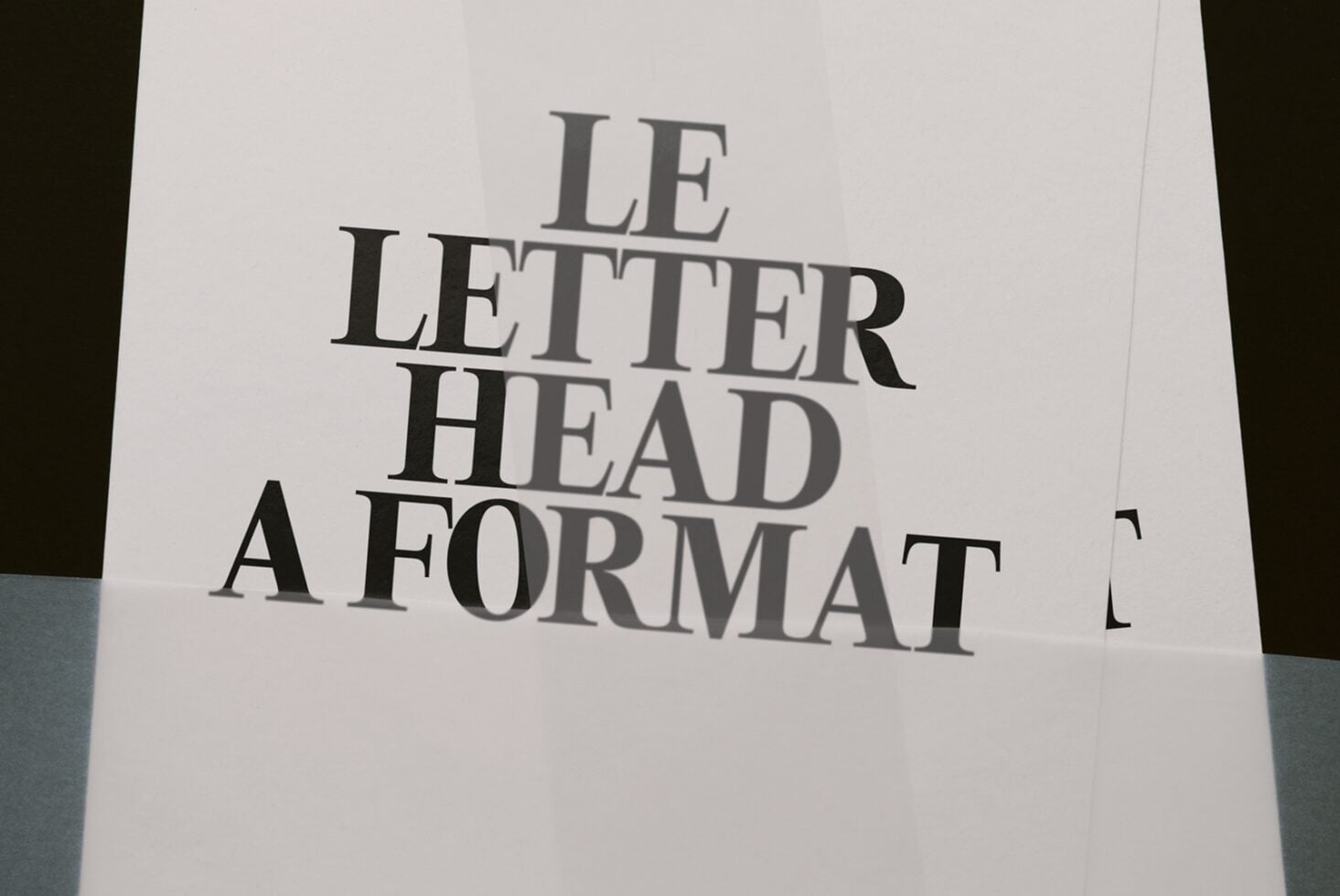 Letterhead mockup shot from above showing serif typography on cream paper with dark edges visible