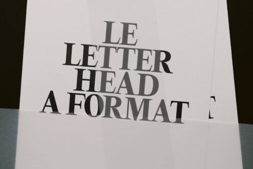 Letterhead mockup shot from above showing serif typography on cream paper with dark edges visible