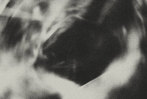 Folded dark fabric with halftone dot texture overlay creating grainy shadow effect
