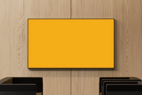 Bright yellow screen mockup hung on light wood wall with black furniture below