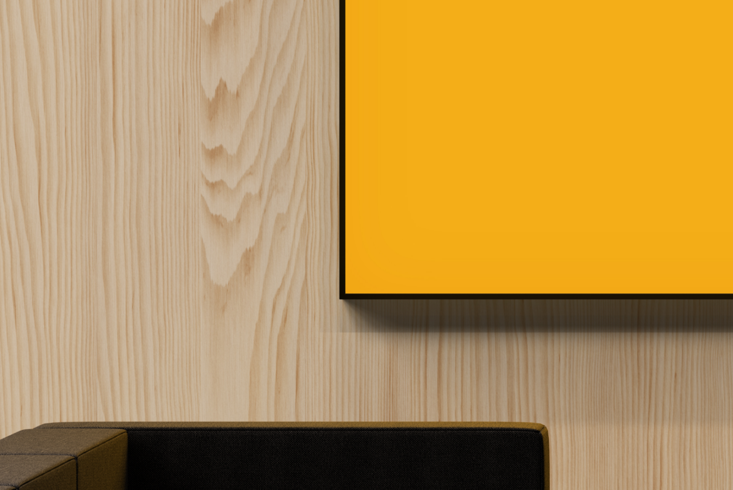 Bright yellow framed poster on light wood wall with black couch below