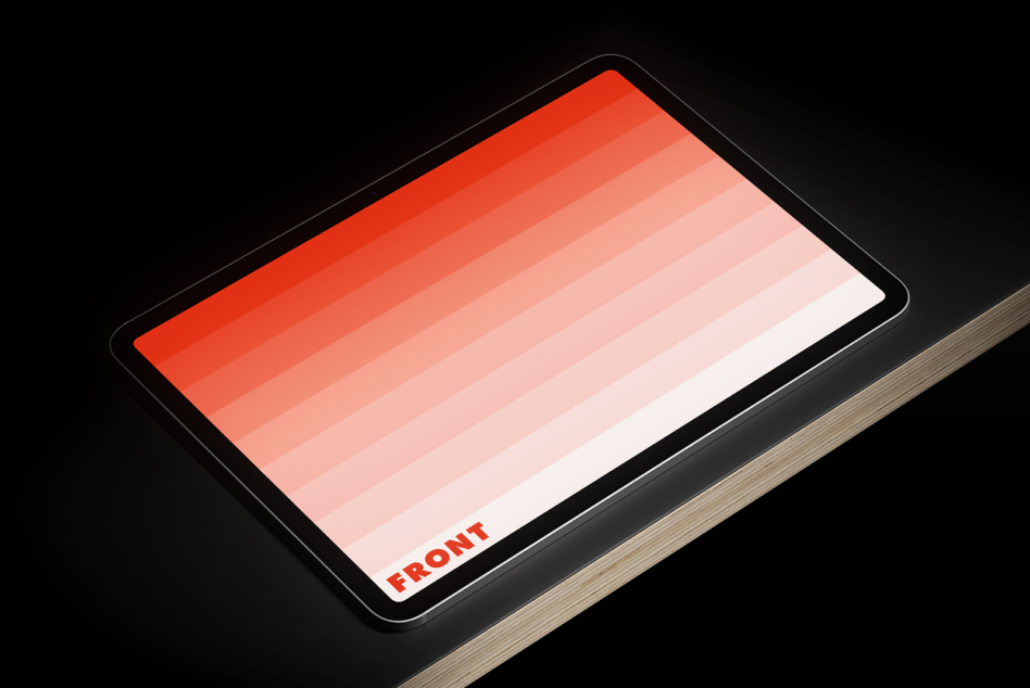 Tablet mockup with red gradient fading to white, black bezel, wooden base, angled view