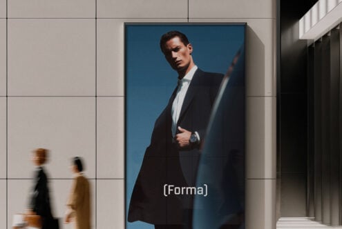 Man in black suit with white shirt on blue background displayed in modern corridor