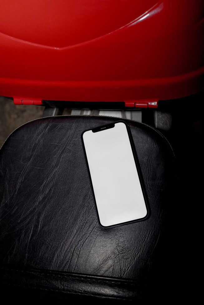 Blank phone screen on black leather chair with red umbrella overhead
