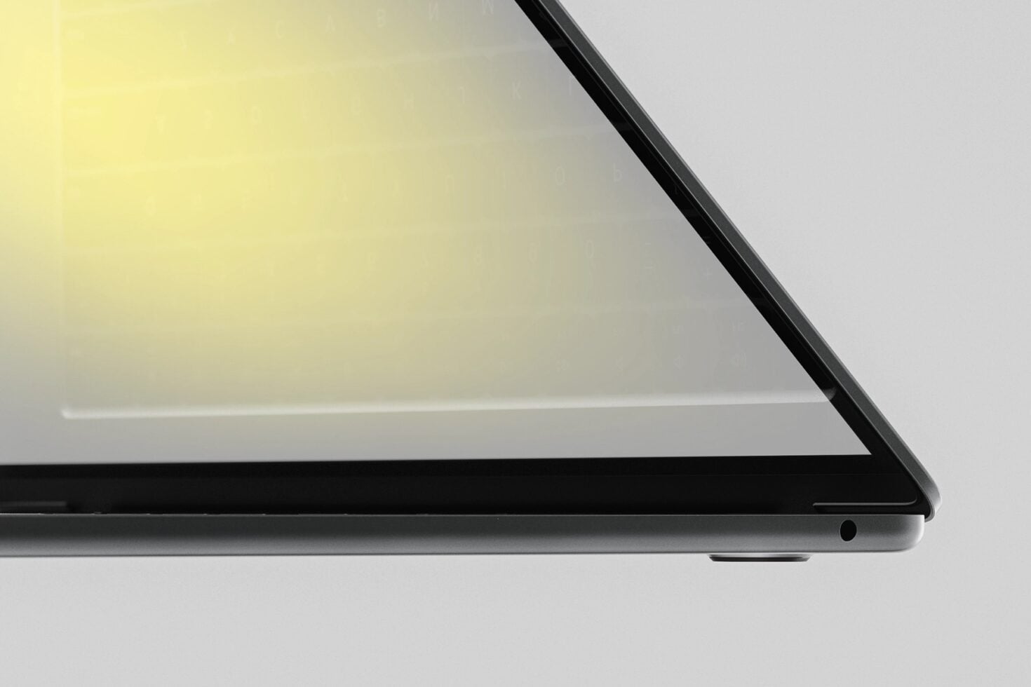 Laptop corner detail showing sleek black bezel with soft yellow gradient on screen
