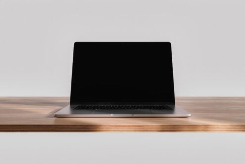 Laptop mockup on wooden desk with blank screen, neutral background