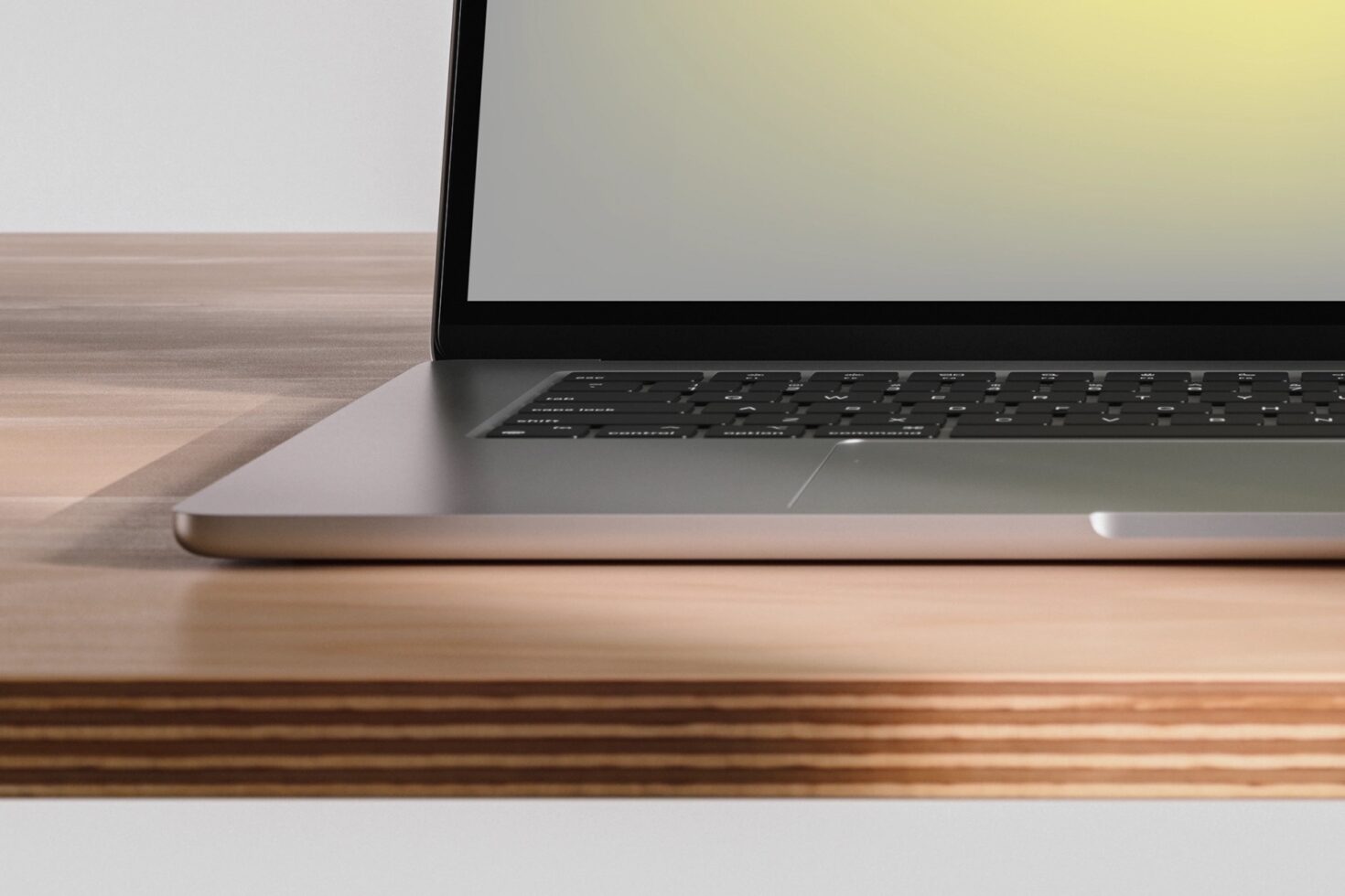 Laptop angled on wooden desk with blank screen, clean minimal workspace setup