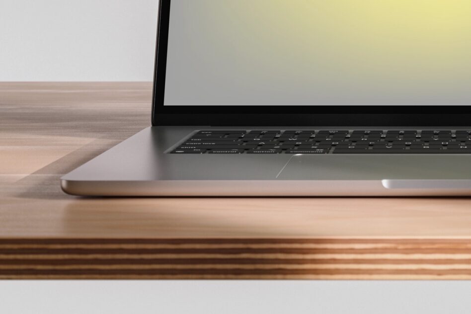 Laptop angled on wooden desk with blank screen, clean minimal workspace setup