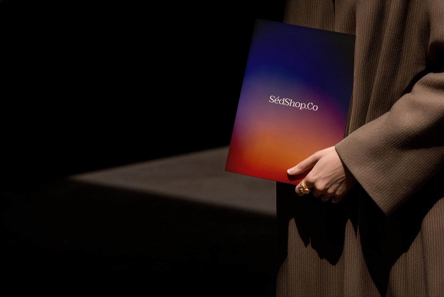 Hand holding gradient notebook mockup with purple to orange fade, SeaShopCo branding visible on cover