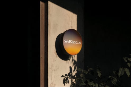Round storefront sign mockup with amber gradient on textured wall with dramatic shadows