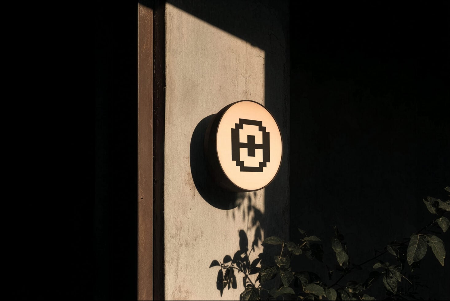 Circular sign with pixelated medical cross mounted on textured wall with dramatic shadow