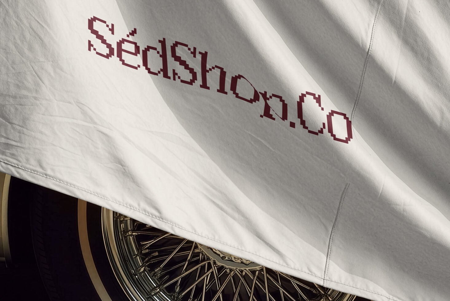 Maroon pixelated text printed on white fabric with natural shadow detail