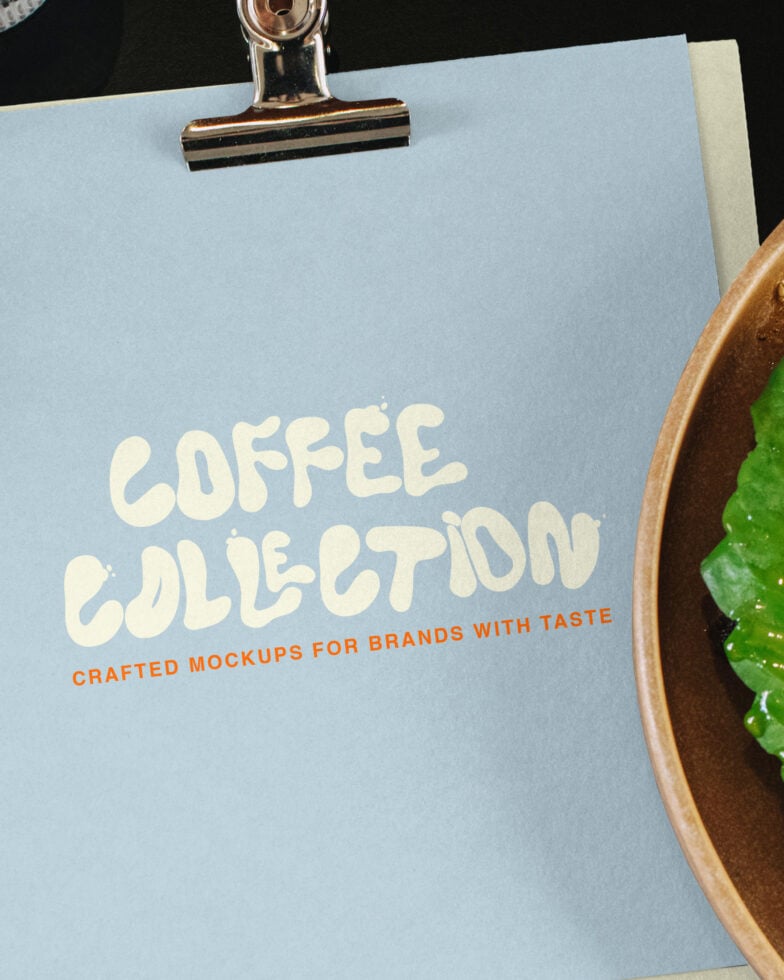 Light blue clipboard with cream text reading "COFFEE COLLECTION" plus orange subheading, gold clip, plant pot edge visible