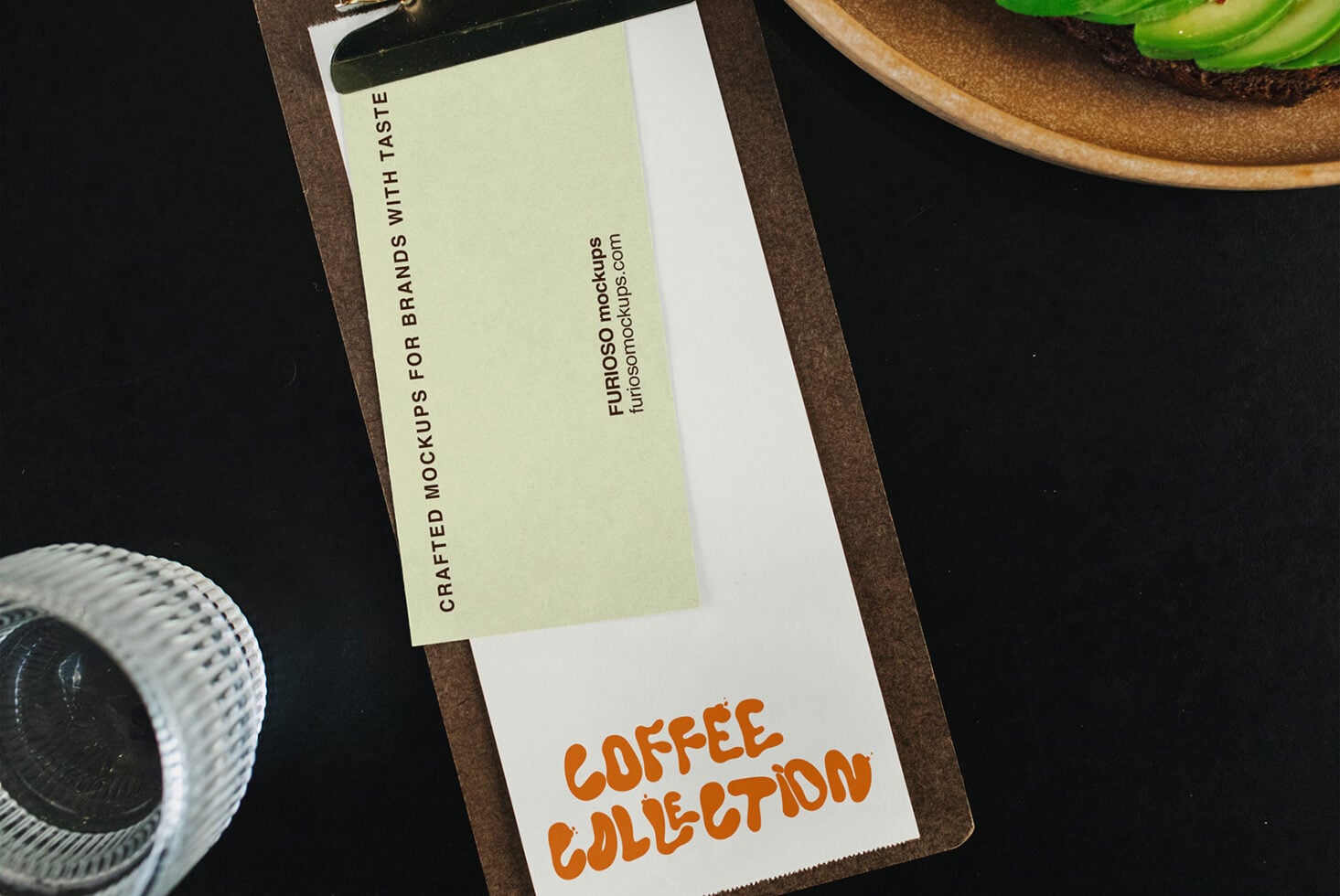 Clipboard mockup with cream label showing "Coffee Collection" branding on dark desk with avocado toast