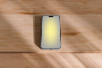 iPhone mockup on wooden desk with natural sunlight casting soft shadows