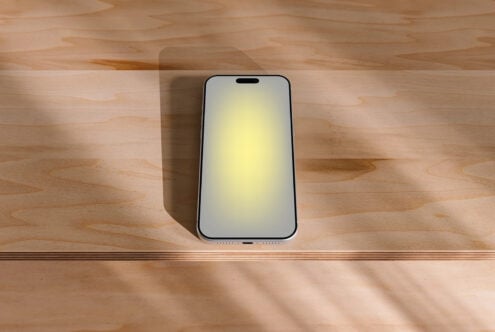 iPhone mockup on wooden desk with natural sunlight casting soft shadows