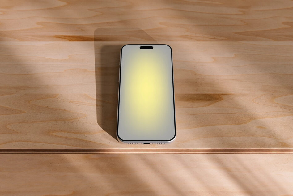 iPhone mockup on wooden desk with natural sunlight casting soft shadows